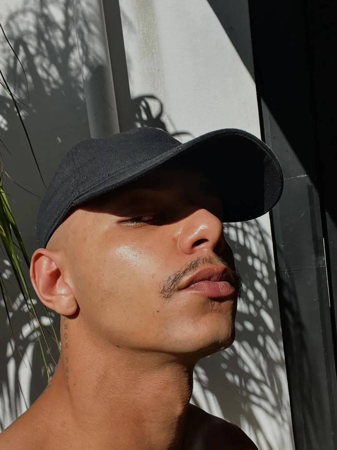 Anderson de boné entre sombras de folhas